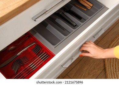 Young Woman Opening Kitchen Drawer With Cutlery, Closeup