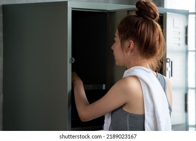 Young Woman Opening Locker In Sports Gym Changing Room. 