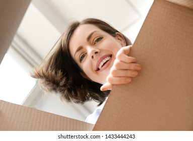 Young Woman Opening Parcel At Home, View From Inside Of Box