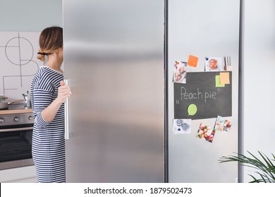 Young Woman Opening Refrigerator In Kitchen