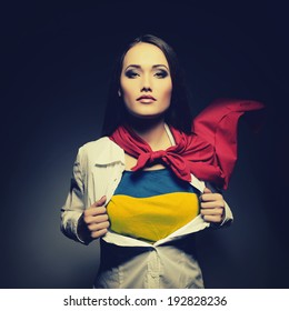 Young woman opening shirt painted in colors of ukrainian flag like superhero. Girl twenty-years-old like young Ukraine fights for independence, democracy and peaceful life. Ukrainian patriot concept.