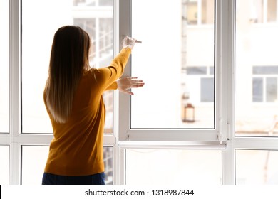 Young woman opening window in flat - Shutterstock ID 1318987844