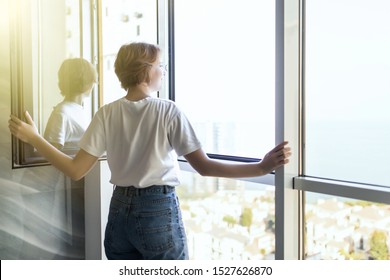 Young Woman Opening Window In Living Room