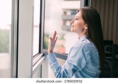 Young Woman Opening Window In Living Room