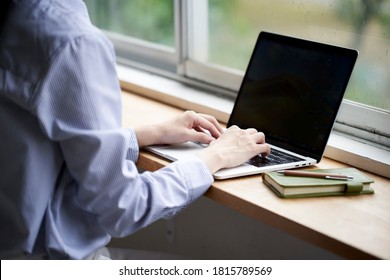 A young woman operating a computer by the window
