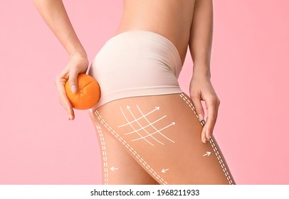 Young woman with orange fruit on color background. Concept of cellulite - Shutterstock ID 1968211933