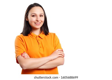 A Young Woman In An Orange Polo Shirt With Her Arms Crossed Looks At The Camera And Smiles. Place For Copy Space. Isolated On White Background