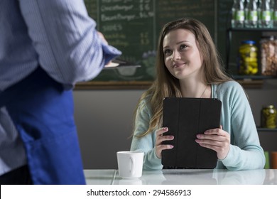 A Young Woman Ordering Food From A Waiter