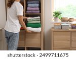 Young woman with organizers folding clean clothes into wardrobe at home, closeup