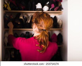 A Young Woman Is Organizing Her Shoe Cupboard At Home