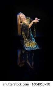 Young woman oriental dancer in national traditional Khaliji dress with feathers on a black background