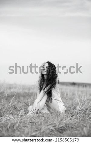 Similar – Beautiful young photographer woman wearing black clothes, sitting on the floor in countryside with her camera