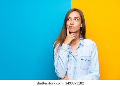 Young woman over colorful background thinking an idea