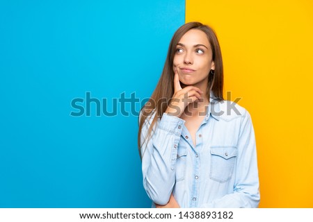 Young woman over colorful background thinking an idea