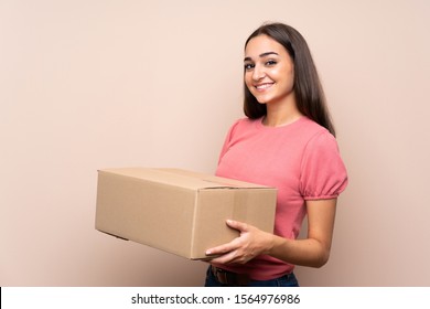 Young woman over isolated background holding a box to move it to another site
