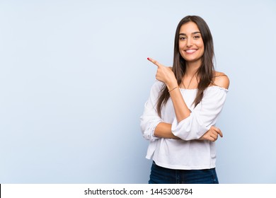 Junge Frau auf einzeln blauem Hintergrund mit Zeigefinger auf der Seite