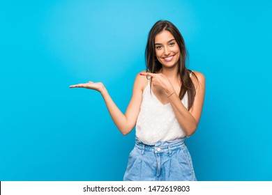 Junge Frau auf einzeln blauem Hintergrund, die Kopienraum auf der Handfläche hält, um eine Anzeige einzufügen