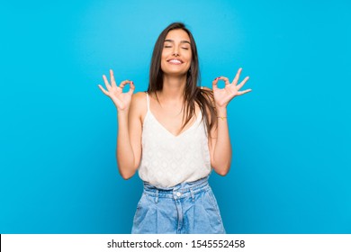 Young woman over isolated blue background in zen pose