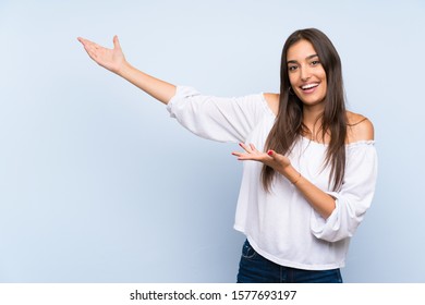 Young woman over isolated blue background extending hands to the side for inviting to come - Shutterstock ID 1577693197