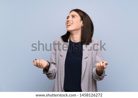 Young woman over isolated blue wall smiling