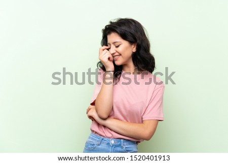 Young woman over isolated green background smiling a lot