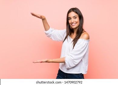 Young woman over isolated pink background holding copyspace to insert an ad - Shutterstock ID 1470902792