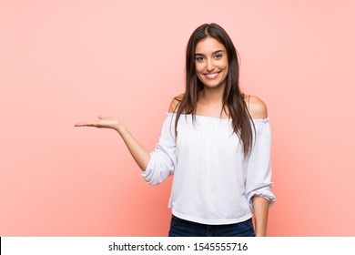 Young woman over isolated pink background holding copyspace imaginary on the palm to insert an ad - Shutterstock ID 1545555716