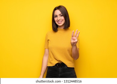 Young Woman Over Yellow Wall Happy And Counting Three With Fingers