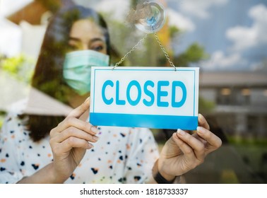 young woman owner with face mask closed store, effect of coronavirus (COVID-19) pandemic - Shutterstock ID 1818733337