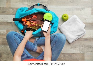 Young Woman Packing Sports Bag On Floor, Top View