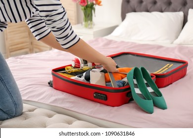 Young Woman Packing Suitcase On Bed