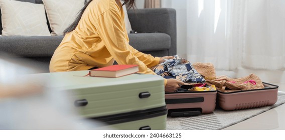 Young woman packs clothes to travel. Prepare your suitcase for your summer vacation trip. Young woman examining jewelry and various items in the suitcase on the carpet at home before traveling. - Powered by Shutterstock