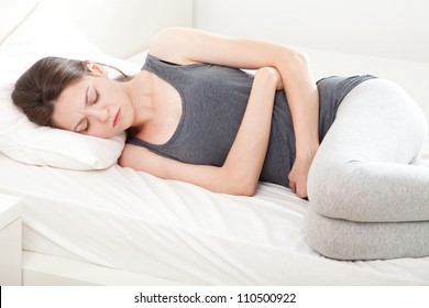 Young Woman In Pain Lying On Bed