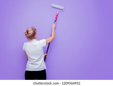 Young woman with paint roller in own house try to painting a room. Real people - Powered by Shutterstock