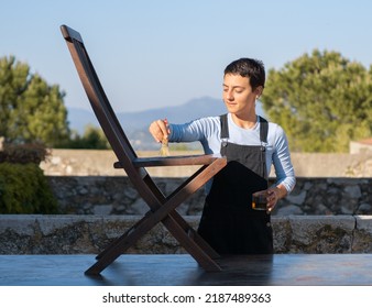 Young Woman Painting Cladding Wooden Chair In Outdoor, DIY Home Improvement.