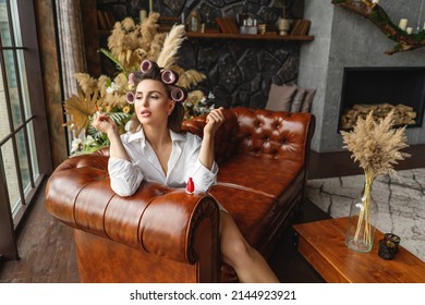 Young Woman Painting Fingernails With Red Enamel While Lying On Sofa, Doing Manicure At Home, Perfect Healthy Nails Care