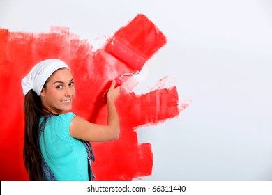 Young Woman Painting House Wall In Red