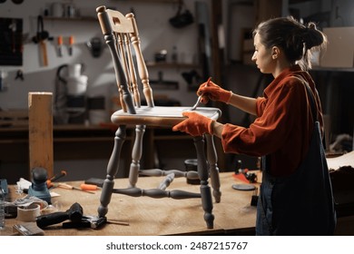 Young woman painting old wooden chair in grey color with paint brush working in her workshop. Restoration of the chair. Painting furniture. renovation, diy and furniture restoration concept. - Powered by Shutterstock