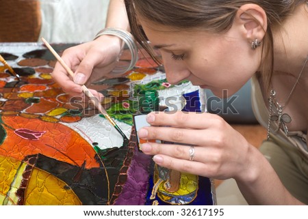 Young woman painting on the glass surface with vitrage dye