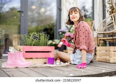 Young Woman Painting Wooden Box In Pink Color, Doing Some Renovating Housework On The Terrace Outdoors. DIY Concept