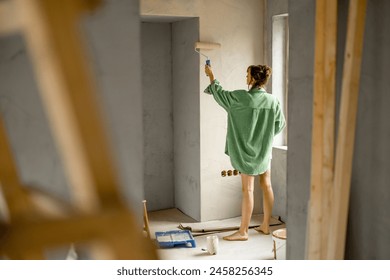 Young woman paints walls while making repairment of a new house. Creative process of home renovation and repair concept - Powered by Shutterstock