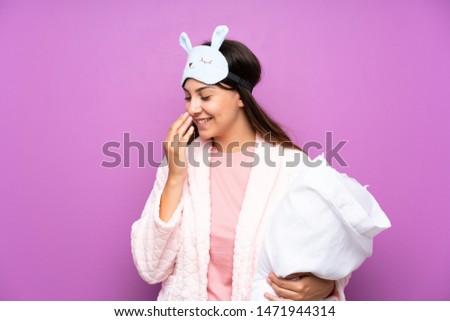 Young woman in pajamas and dressing gown over isolated purple background smiling a lot