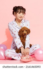 Young Woman In Pajamas With A Toy Poodle