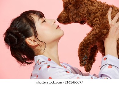 Young Woman In Pajamas With A Toy Poodle