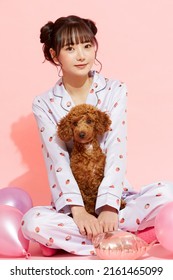 Young Woman In Pajamas With A Toy Poodle