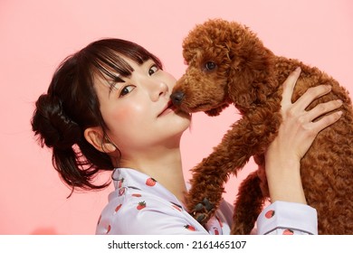 Young Woman In Pajamas With A Toy Poodle