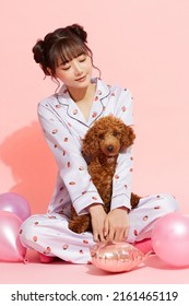 Young Woman In Pajamas With A Toy Poodle