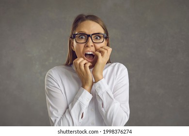 Young woman panicking. Studio portrait of office worker in white shirt and glasses screaming loudly scared by something terrible, witnessing awful crime, or afraid of danger. Fear and fright concept