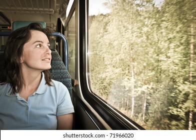 Young Woman Passanger Sitting Inside Train And Looking Trough Window