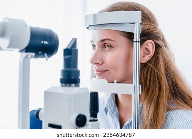 Young woman patient undergoing ophthalmic vision check up with slit-lamp retinoscope modern apparatus in clinic hospital. : side view. Ophthalmology concept
